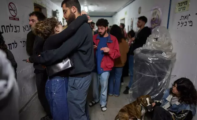 People take shelter as air raid sirens signal a warning of incoming Iranian missiles in Tel Aviv, Israel, Monday, March 16, 2026. (AP Photo/Ohad Zwigenberg)