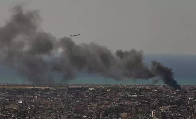 A Middle East Airlines plane takes off from Rafik Hariri International Airport as smoke rises from the site of an Israeli airstrike in Dahiyeh, Beirut's southern suburbs, Lebanon, Tuesday, March 17, 2026. (AP Photo/Hassan Ammar)