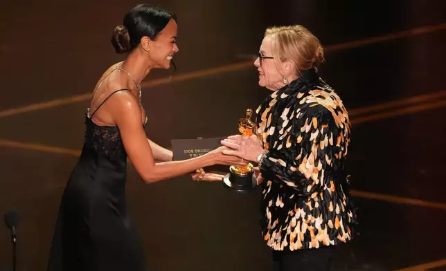 Zoe Saldaña, left, presents the award for best performance by an actress in a supporting role to Amy Madigan for "Weapons" on Sunday, March 15, 2026, at the Dolby Theatre in Los Angeles. (AP Photo/Chris Pizzello)