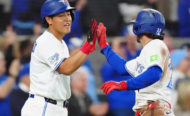 Toronto Blue Jays' Kazuma Okamoto (left) and Ernie Clement (22) celebrate after they both scored during the fifth inning of a baseball game against the Athletics in Toronto on Friday, March 27, 2026. (Frank Gunn/The Canadian Press via AP)