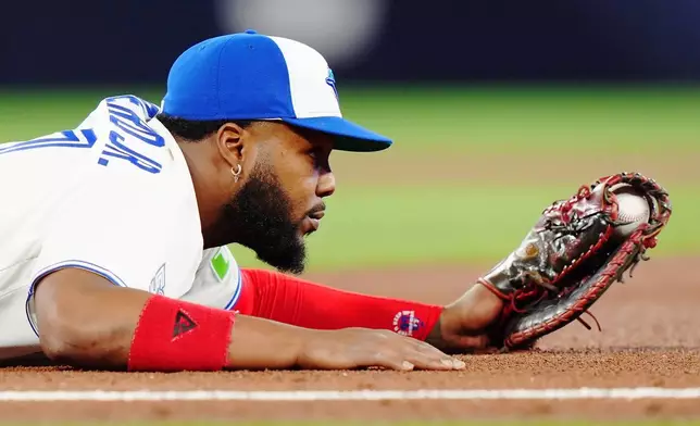 Toronto Blue Jays first baseman Vladimir Guerrero Jr. (27) holds on to the ball after forcing out Athletics' Tyler Soderstrom during the fourth inning of a baseball game in Toronto on Friday, March 27, 2026. (Nathan Denette/The Canadian Press via AP)