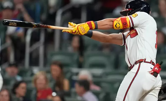 Atlanta Braves' Mauricio Dubón (14) hits a two-RBI triple against the Kansas City Royals during the seventh inning of an opening-day baseball game, Friday, March 27, 2026, in Atlanta. (AP Photo/Mike Stewart)