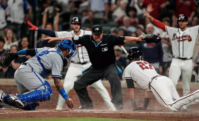 Atlanta Braves third baseman Austin Riley (27) is safe on a two-RBI triple hit by Atlanta Braves' Mauricio Dubón in the seventh inning of an opening-day baseball game against the Kansas City Royals, Friday, March 27, 2026, in Atlanta. (AP Photo/Mike Stewart)