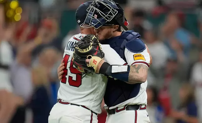 Atlanta Braves pitcher Tyler Kinley (45) celebrates victory with Atlanta Braves' Jonah Heim over the Kansas City Royals after an opening-day baseball game, Friday, March 27, 2026, in Atlanta. (AP Photo/Mike Stewart)