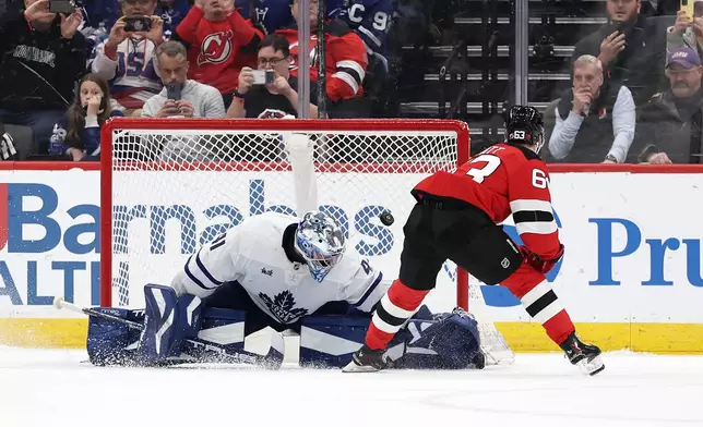 New Jersey Devils left wing Jesper Bratt (63) scores a goal past Toronto Maple Leafs goaltender Anthony Stolarz during a shootout of an NHL hockey game, Wednesday, March 4, 2026, in Newark, N.J. (AP Photo/Adam Hunger)