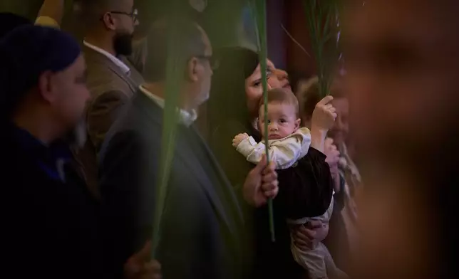 Parishioners hold palm branches during the Palm Sunday celebration at the Our Lady of Hadat Church in Beirut, Lebanon, Sunday, March 29, 2026. (AP Photo/Emilio Morenatti)