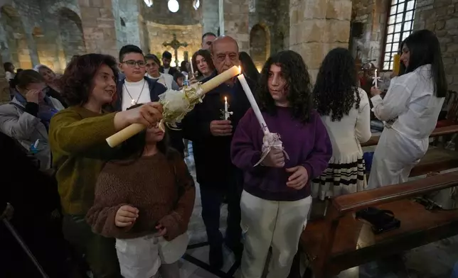 Worshipers light candles as they attend Palm Sunday Mass procession at Saint Thomas Cathedral, in the southern port city of Tyre, south Lebanon, Sunday, March 29, 2026. (AP Photo/Hussein Malla)