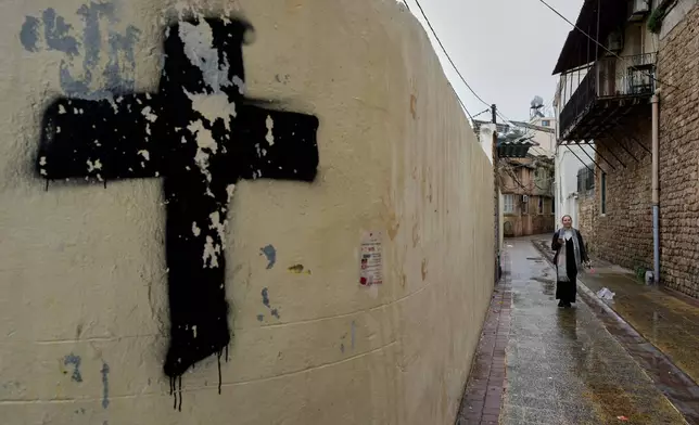 A woman walks in one of the Christian alleys on her way to attend Palm Sunday Mass at Saint Thomas Cathedral, in the southern port city of Tyre, south Lebanon, Sunday, March 29, 2026. (AP Photo/Hussein Malla)