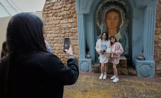 A Christian woman takes pictures of her daughters outside a church, as they celebrate Palm Sunday in the southern port city of Tyre, south Lebanon, Sunday, March 29, 2026. (AP Photo/Hussein Malla)
