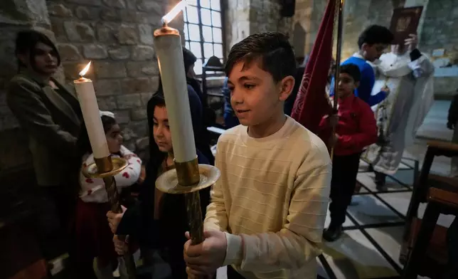 Boys hold candles during Palm Sunday Mass procession at Saint Thomas Cathedral, in the southern port city of Tyre, south Lebanon, Sunday, March 29, 2026. (AP Photo/Hussein Malla)