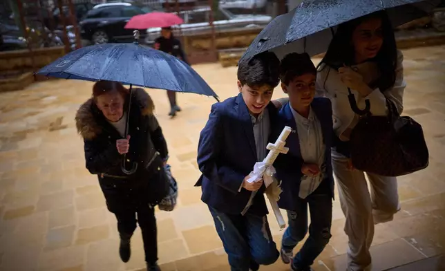 Worshippers shelter from the rain under umbrellas as they arrive at a church to attend a Palm Sunday Mass in Beirut, Lebanon, Sunday, March 29, 2026. (AP Photo/Emilio Morenatti)