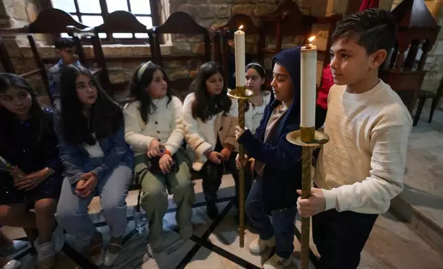 Boys hold candles during Palm Sunday Mass procession at Saint Thomas Cathedral, in the southern port city of Tyre, south Lebanon, Sunday, March 29, 2026. (AP Photo/Hussein Malla)
