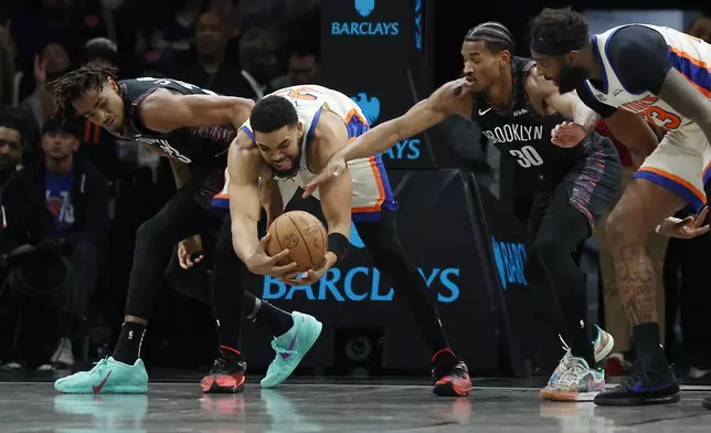 Brooklyn Nets center Nic Claxton, left, and Brooklyn Nets guard Ochai Agbaji (30) reach for the ball against New York Knicks center Karl-Anthony Towns, second from left, during the first half of an NBA basketball game, Friday, March 20, 2026, in New York. (AP Photo/Heather Khalifa)