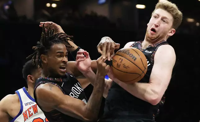 Brooklyn Nets center Nic Claxton, left, and teammate Danny Wolf, right, both go for the rebound during the second half of an NBA basketball game against the New York Knicks, Friday, March 20, 2026, in New York. (AP Photo/Heather Khalifa)