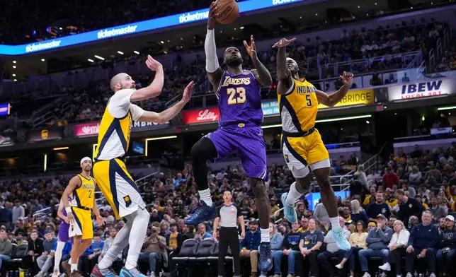 Los Angeles Lakers forward LeBron James (23) shoots between Indiana Pacers forward Jarace Walker (5) and center Jay Huff (32) during the second half of an NBA basketball game in Indianapolis, Wednesday, March 25, 2026. (AP Photo/Michael Conroy)