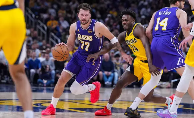 Los Angeles Lakers guard Luka Doncic (77) drives past Indiana Pacers guard Kobe Brown (24) during the second half of an NBA basketball game in Indianapolis, Wednesday, March 25, 2026. (AP Photo/Michael Conroy)