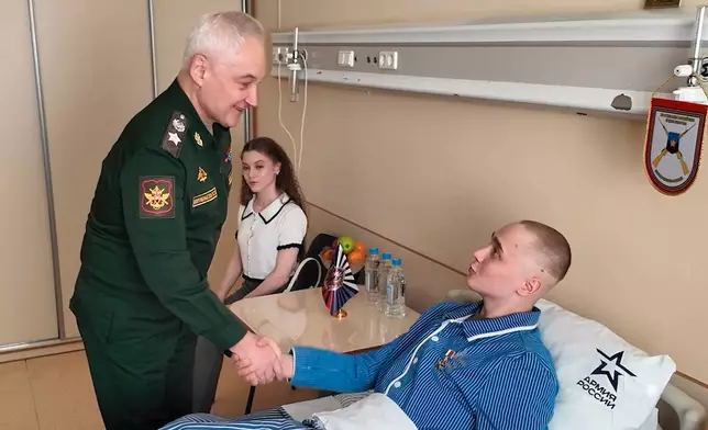 In this image made from video provided by Russian Defense Ministry Press Service on Tuesday, March 24, 2026, Russian Minister of Defense Andrei Belousov, left, presents the "Gold Star" Hiro of Russia medal to a participant of the military action in Ukraine, Private Sergei Yarashev, at The National Medical Research Center of Surgery in Moscow. (Russian Defense Ministry Press Service via AP)