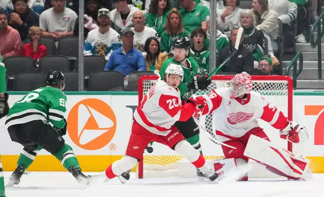 A shot by Dallas Stars left wing Michael Bunting, far left, enters the net of Detroit Red Wings goaltender John Gibson, right, for a goal during the second period of an NHL hockey game Saturday, March 14, 2026, in Dallas. (AP Photo/Julio Cortez)