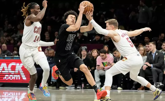 Brooklyn Nets guard Nolan Traore (88) drives past Cleveland Cavaliers guard Sam Merrill (5) and Cleveland Cavaliers guard Keon Ellis (14) during the first half of an NBA basketball game, Sunday, March 1, 2026, in New York. (AP Photo/Yuki Iwamura)