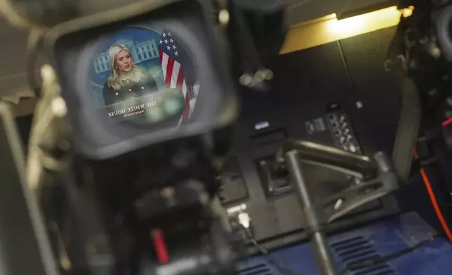 White House press secretary Karoline Leavitt is reflected in a video camera lens as she speaks during a briefing in the James Brady Press Briefing Room at the White House, Wednesday, Feb. 18, 2026, in Washington. (AP Photo/Nathan Howard)