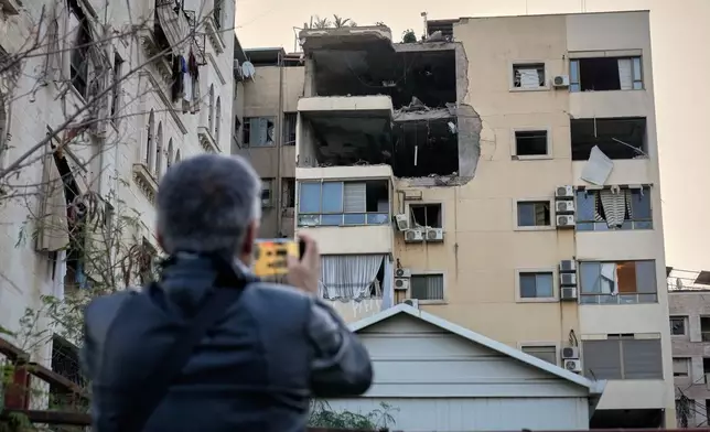 A man takes pictures of the damage in an apartment building after it was hit by an Israeli airstrike in Dahiyeh, Beirut's southern suburb, Lebanon, Monday, March 2, 2026. (AP Photo/Hussein Malla)