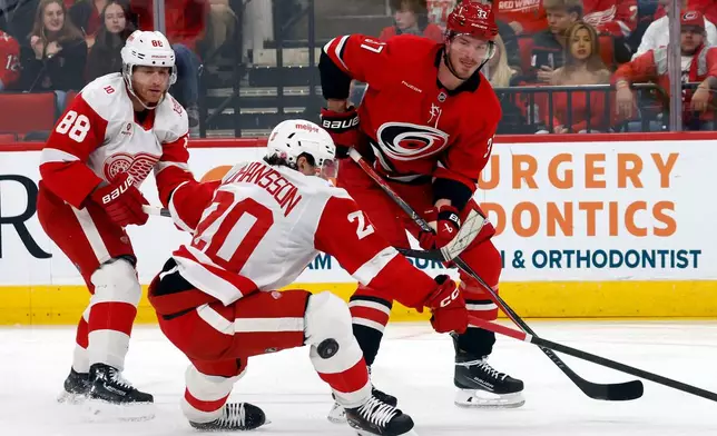 Carolina Hurricanes' Andrei Svechnikov (37) passes the puck around Detroit Red Wings' Albert Johansson (20) and Patrick Kane (88) during the second period of an NHL hockey game in Raleigh, N.C., Saturday, Feb. 28, 2026. (AP Photo/Karl DeBlaker)