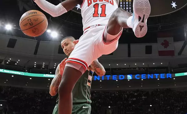 Chicago Bulls forward Leonard Miller (11) hangs from the rim after dunking during the second half of an NBA basketball game against the Milwaukee Bucks in Chicago, Sunday, March 1, 2026. (AP Photo/Nam Y. Huh)