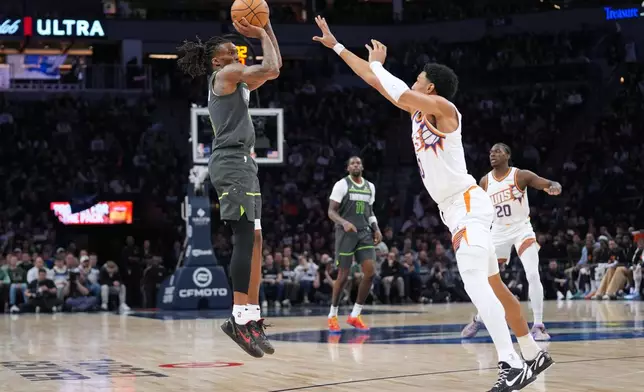 Minnesota Timberwolves guard Bones Hyland, left, shoots over Phoenix Suns forward Ryan Dunn during the first half of an NBA basketball game, Tuesday, March 17, 2026, in Minneapolis. (AP Photo/Abbie Parr)