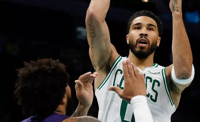 Boston Celtics forward Jayson Tatum, right, passes over Charlotte Hornets forward Miles Bridges during the second half of an NBA basketball game in Charlotte, N.C., Sunday, March 29, 2026. (AP Photo/Nell Redmond)