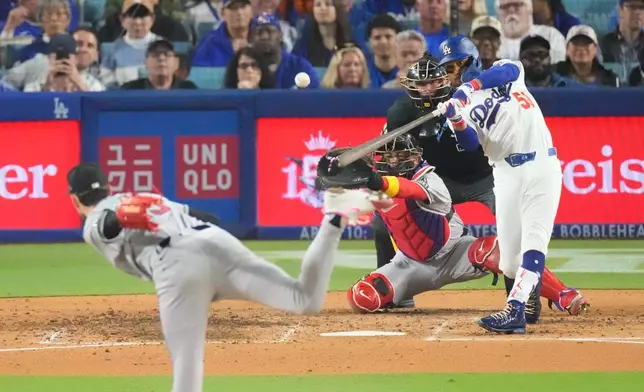 Los Angeles Dodgers' Mookie Betts, right, hits a three-run home run as Arizona Diamondbacks starting pitcher Ryne Nelson, left, and catcher Gabriel Moreno watch during the third inning of a baseball game Friday, March 27, 2026, in Los Angeles. (AP Photo/Mark J. Terrill)