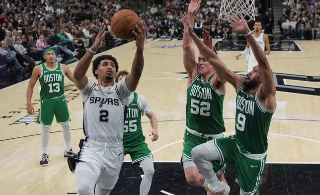 San Antonio Spurs guard Dylan Harper (2) drives to the basket against Boston Celtics guard Derrick White (9) and center Luka Garza (52) during the second half of an NBA basketball game in San Antonio, Tuesday, March 10, 2026. (AP Photo/Eric Gay)