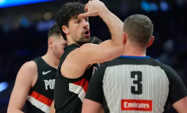 Portland Trail Blazers forward Deni Avdija talks with referee Nick Buchert (3) during the first half of an NBA basketball game against the Dallas Mavericks, Friday, March 27, 2026, in Portland, Ore. (AP Photo/Jenny Kane)