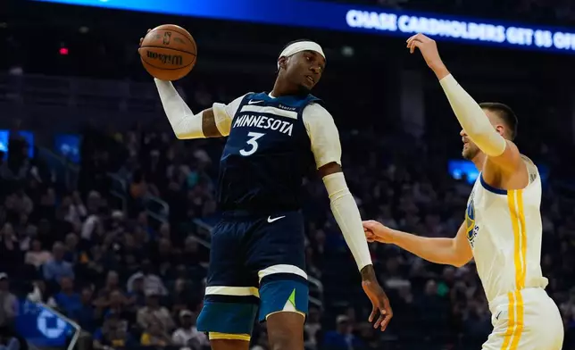 Minnesota Timberwolves forward Jaden McDaniels (3) rebounds the ball next to Golden State Warriors center Kristaps Porzingis (7) during the first half of an NBA basketball game Friday, March 13, 2026, in San Francisco. (AP Photo/Godofredo A. Vásquez)