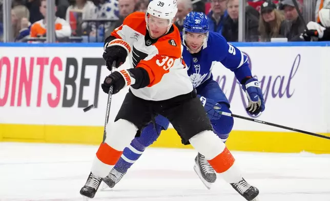 Philadelphia Flyers' Matvei Michkov (39) passes the puck while under pressure from Toronto Maple Leafs' John Tavares (91) during first-period NHL hockey game action in Toronto, Monday, March 2, 2026. (Frank Gunn/The Canadian Press via AP)