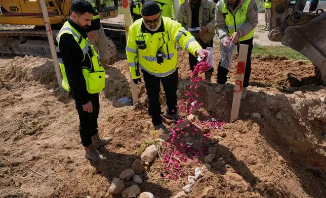 A paramedic scatters flower petals on the grave of his comrade who was killed in an Israeli airstrike, at a temporary mass grave in Tyre, south Lebanon, Wednesday, March 25, 2026. (AP Photo/Hussein Malla)