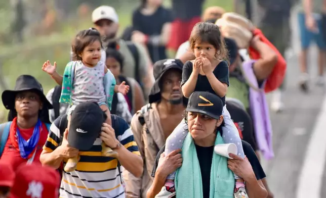 Migrants, some carrying children, walk on the highway through the municipality of Huehuetan, Chiapas state, Mexico, Wednesday, March 25, 2026, after leaving Tapachula the previous night. (AP Photo/Edgar H. Clemente)