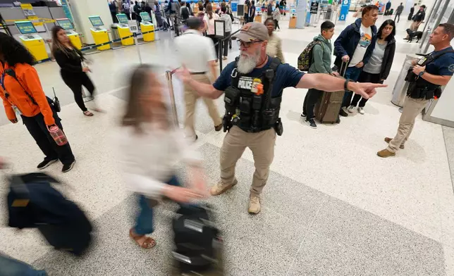 A Federal immigration officer directs passengers through a security checkpoint line at George Bush Intercontinental Airport Wednesday, March 25, 2026, in Houston. (AP Photo/David J. Phillip)