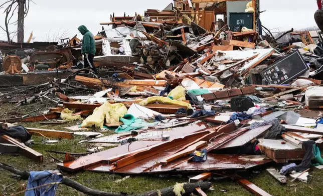 A person searches through his belongings amid debris in the aftermath of a powerful storm that ripped through the area a day earlier, in Aroma Park, Ill., Wednesday, March 11, 2026. (AP Photo/Nam Y. Huh)
