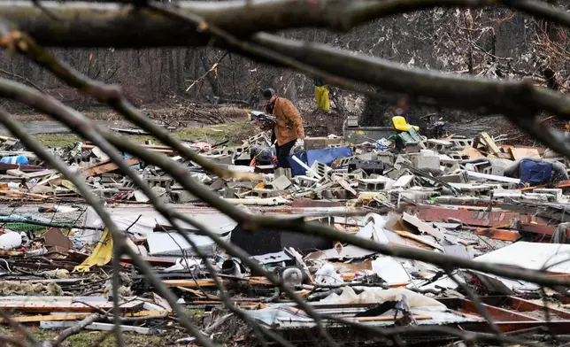 A person searches through his belongings amid debris in the aftermath of a powerful storm that ripped through the area a day earlier, in Aroma Park, Ill., Wednesday, March 11, 2026. (AP Photo/Nam Y. Huh)
