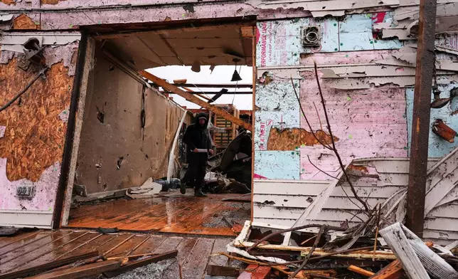 Josh Johnson searches through his belongings at a damaged home in the aftermath of a powerful storm that ripped through the area a day earlier, in Aroma Park, Ill., Wednesday, March 11, 2026. (AP Photo/Nam Y. Huh)