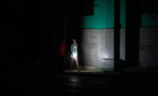 People walk on a street during a blackout in Havana, Cuba, Saturday, March 21, 2026. (AP Photo/Ramon Espinosa)