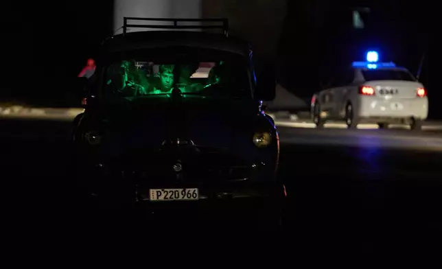 People are seen waiting in a car in the dark during a blackout in Havana, Cuba, Saturday, March 21, 2026. (AP Photo/Ramon Espinosa)