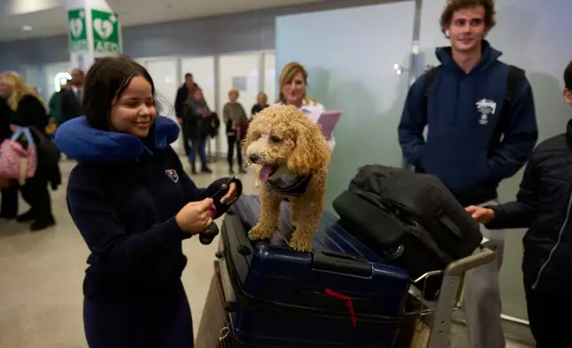 A repatriated Greek young woman and her dog arrive at Athens International Airport Eleftherios Venizelos on Wednesday, March 18, 2026, after being evacuated from Abu Dhabi amid the escalating U.S.-Israeli conflict with Iran. (AP Photo/Petros Giannakouris)