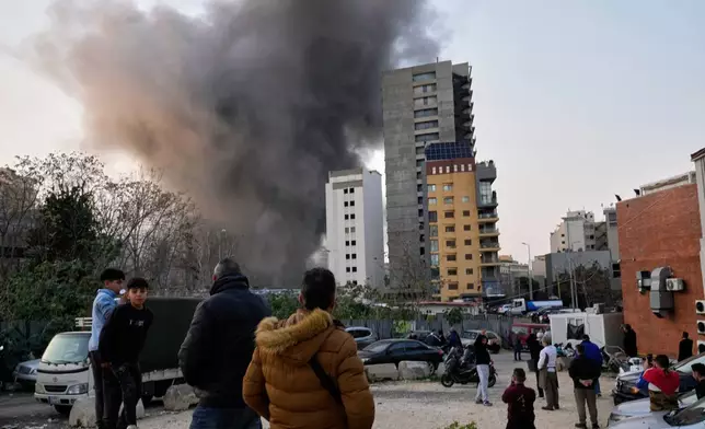 Residents watch as smoke rises from a nearby building during an Israeli strike in central Beirut, Lebanon, Thursday, March 12, 2026. (AP Photo/Hussein Malla)