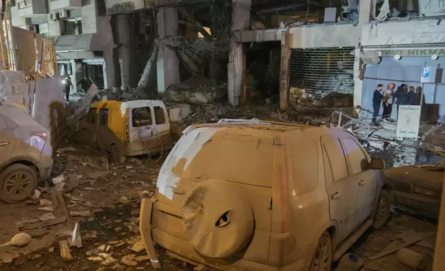 People inspect the site of a destroyed branch of Al-Qard Al-Hassan, a non-bank financial institution run by Hezbollah, which was hit by an Israeli airstrike in central Beirut, Thursday, March 12, 2026. (AP Photo/Hussein Malla)