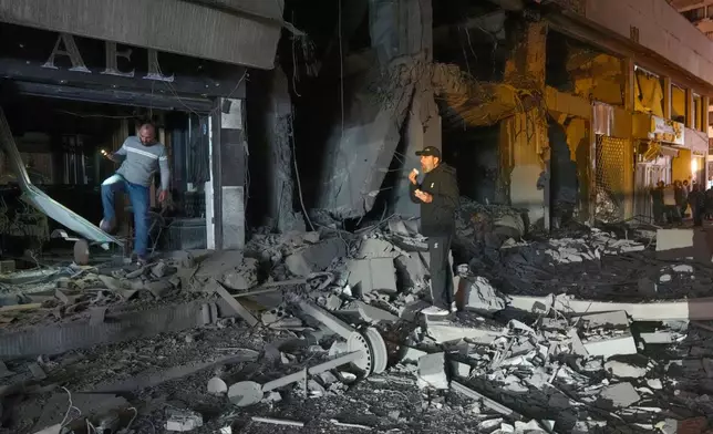 People check the site of a destroyed branch of Al-Qard Al-Hassan, a non-bank financial institution run by Hezbollah, which was hit by an Israeli airstrike in central Beirut, Thursday, March 12, 2026. (AP Photo/Hussein Malla)