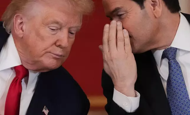 President Donald Trump speaks with Secretary of State Marco Rubio during a roundtable discussion on college sports in the East Room of the White House, Friday, March 6, 2026, in Washington. (AP Photo/Julia Demaree Nikhinson)