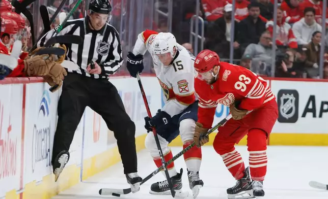 Florida Panthers center Anton Lundell (15) and Detroit Red Wings right wing Alex DeBrincat (93) battle for the puck while avoiding a referee, left, during the first period of an NHL hockey game Friday, March 6, 2026, in Detroit. (AP Photo/Duane Burleson)