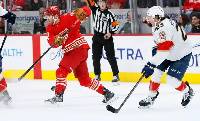 Detroit Red Wings left wing J.T. Compher, left, is pressured by Florida Panthers center Carter Verhaeghe (23) while passing the puck during the first period of an NHL hockey game Friday, March 6, 2026, in Detroit. (AP Photo/Duane Burleson)