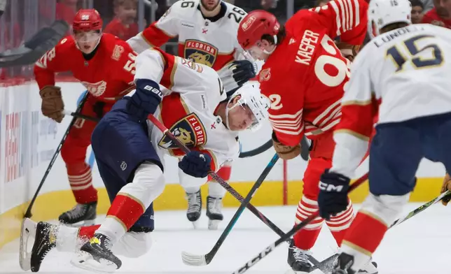 Florida Panthers defenseman Niko Mikkola (77) tries to clear the puck against Detroit Red Wings center Marco Kasper (92) during the second period of an NHL hockey game Friday, March 6, 2026, in Detroit. (AP Photo/Duane Burleson)